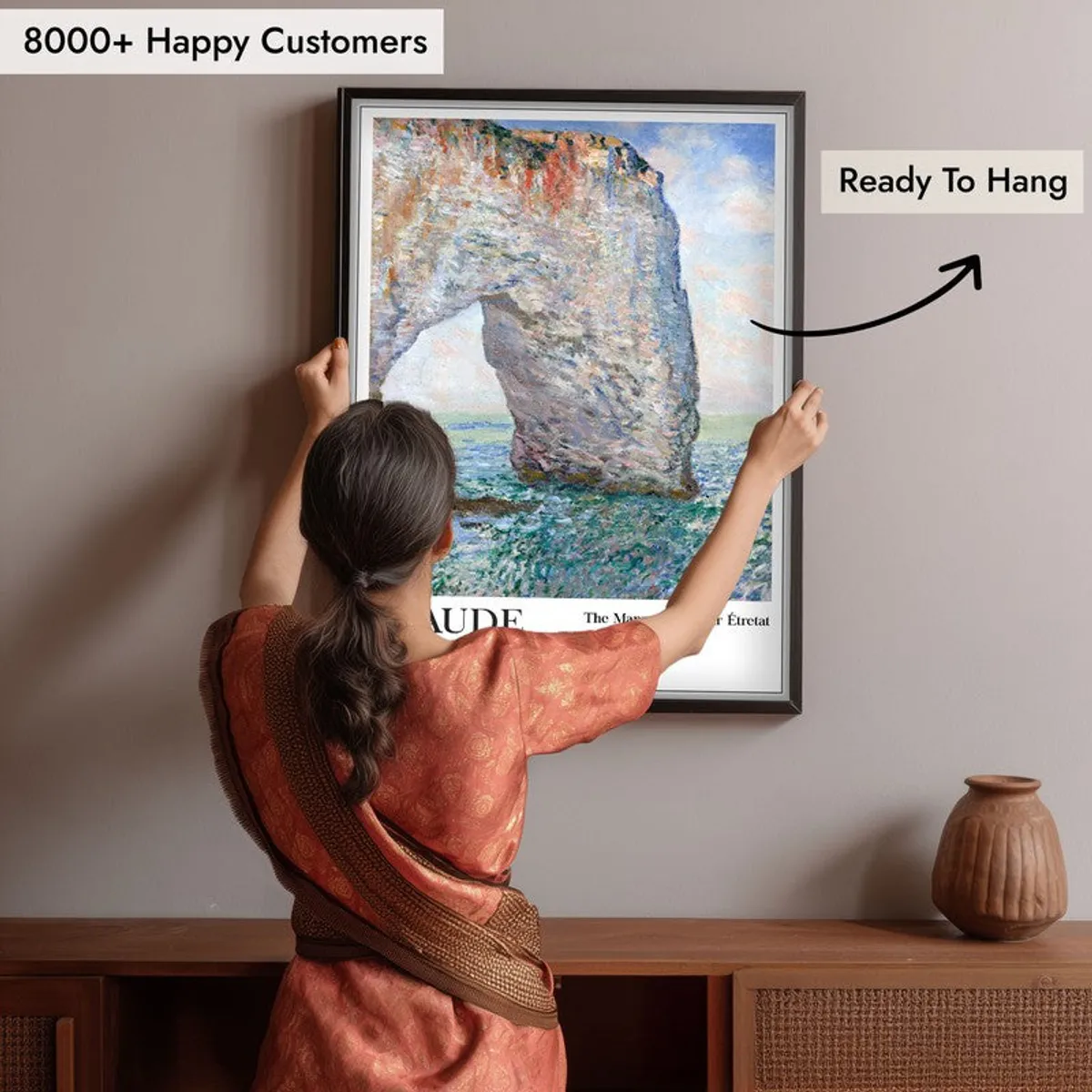 Person hanging a large framed seascape wall painting above a wooden console