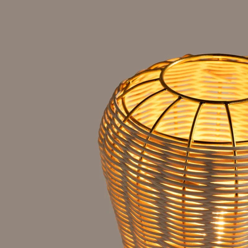 Close-up of the rounded rattan lamp shade with gold metal framing, shown lit