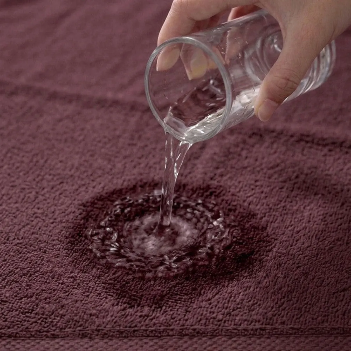 Water being poured onto the textured surface of a purple towel
