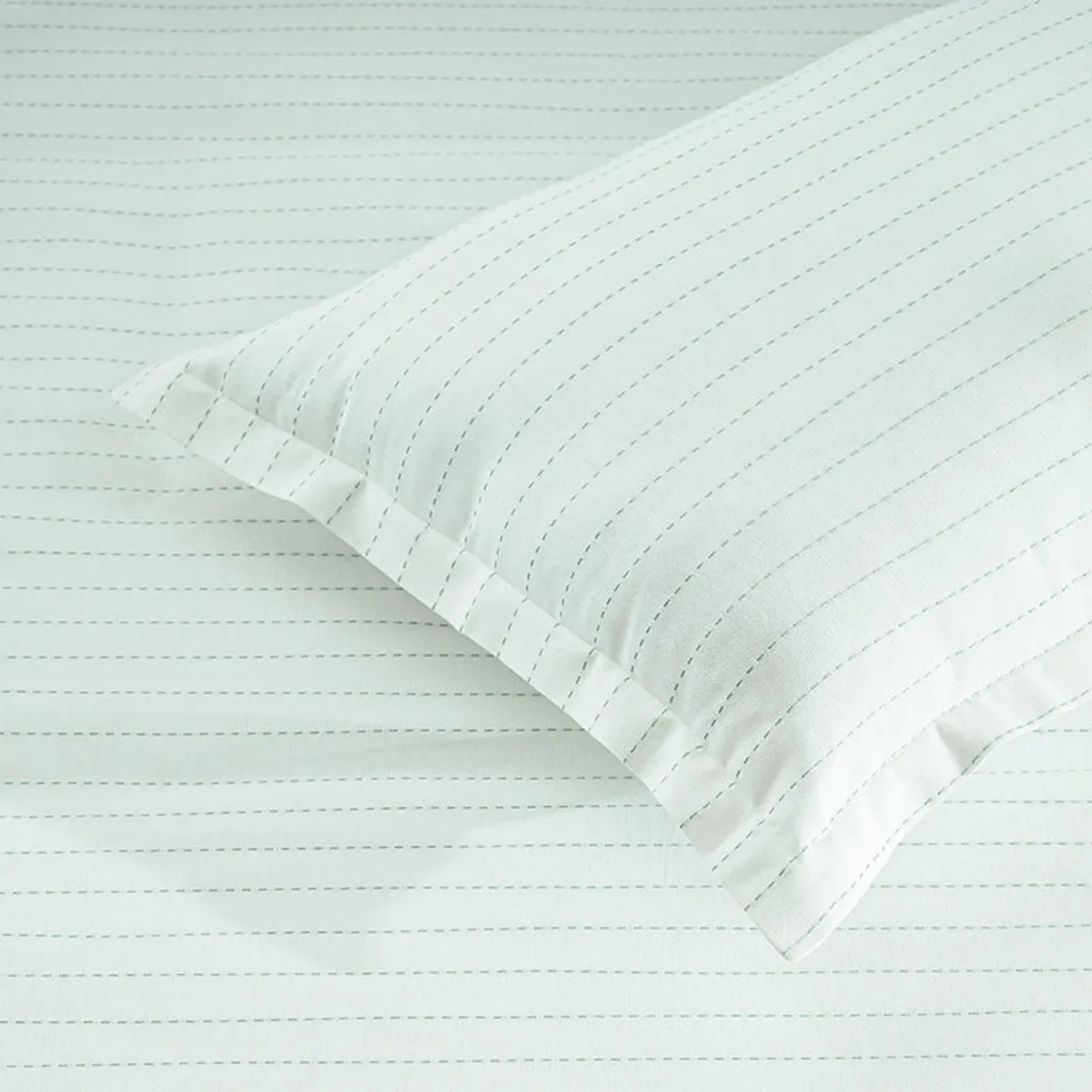 Close view of white bedding with fine parallel stripe detailing
