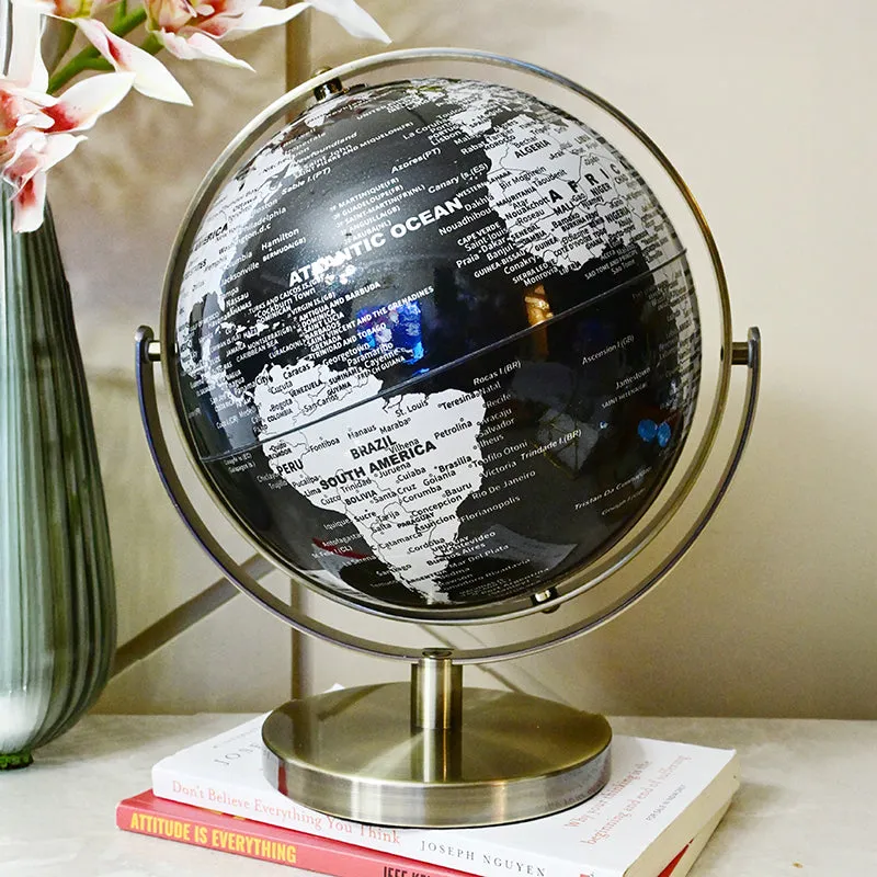 Glossy black globe showpiece on stacked books beside a vase with pink flowers