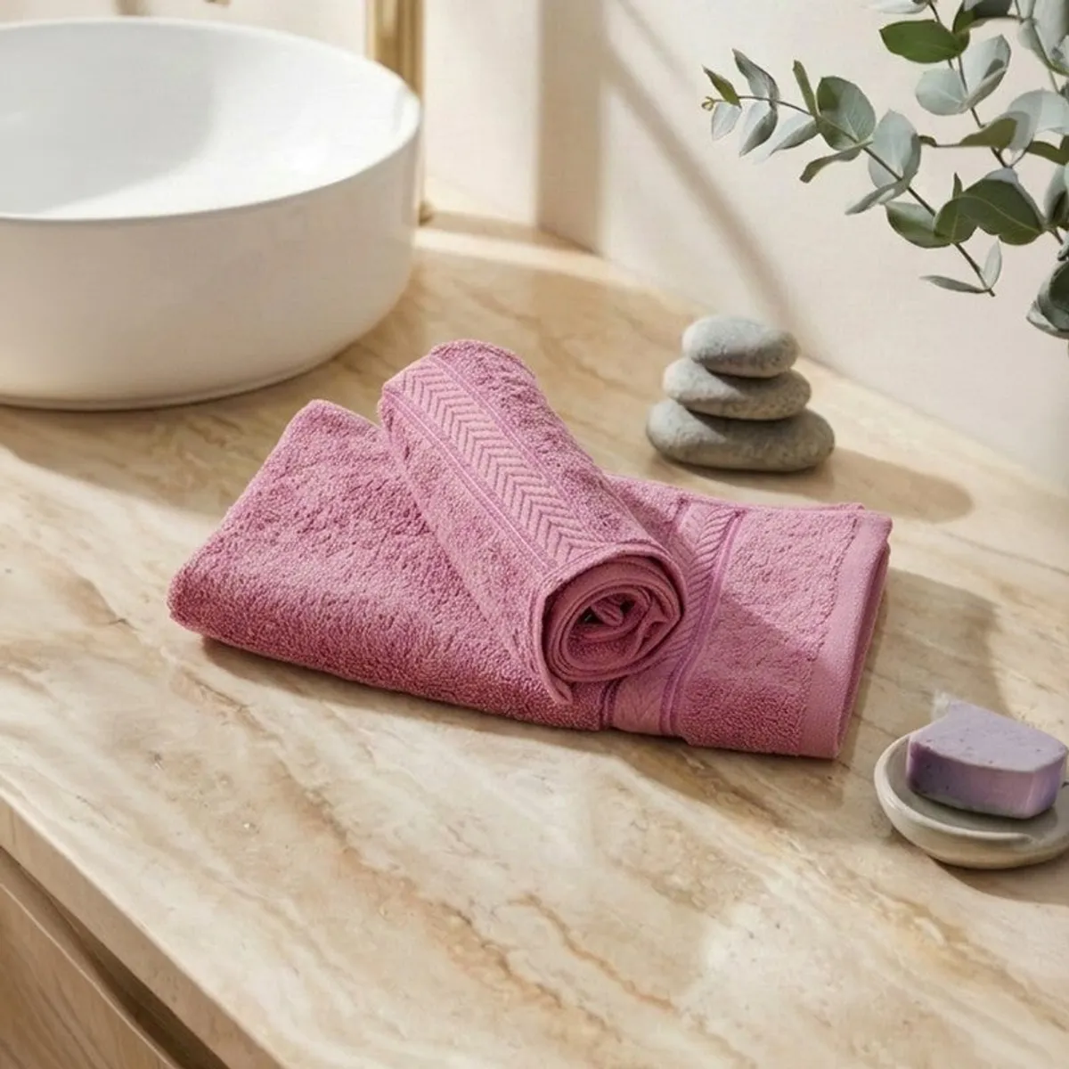 Two pink cotton hand towels folded on a bathroom counter