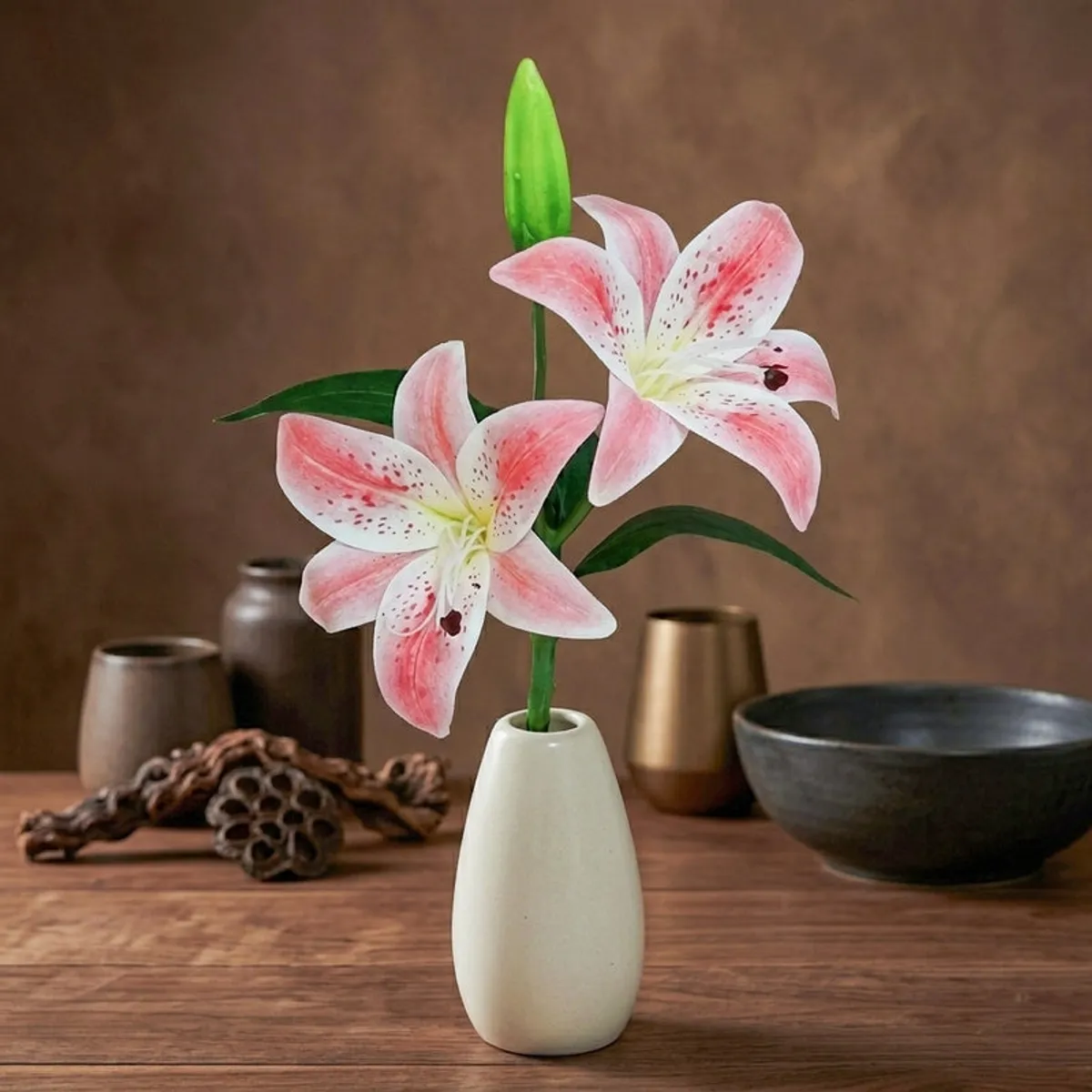 Pink artificial lily flower arranged in a beige vase against a dark backdrop