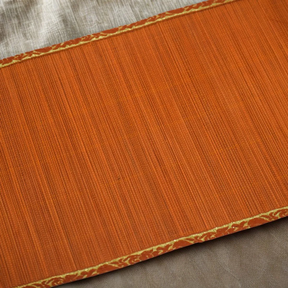 Close view of the orange runner's fine textured surface and decorative border
