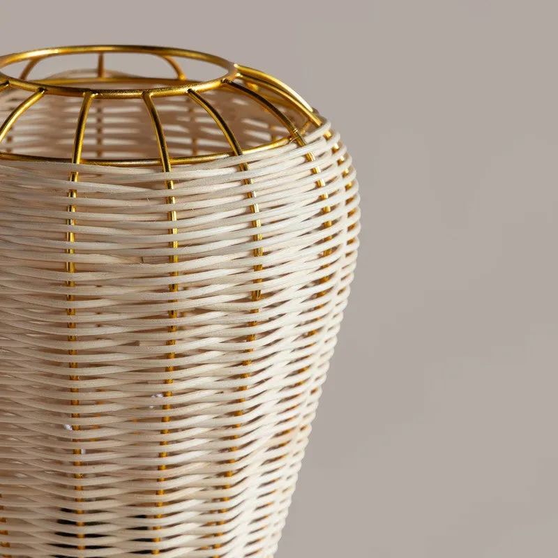Close-up of the beige rattan shade and gold metal frame of a table lamp