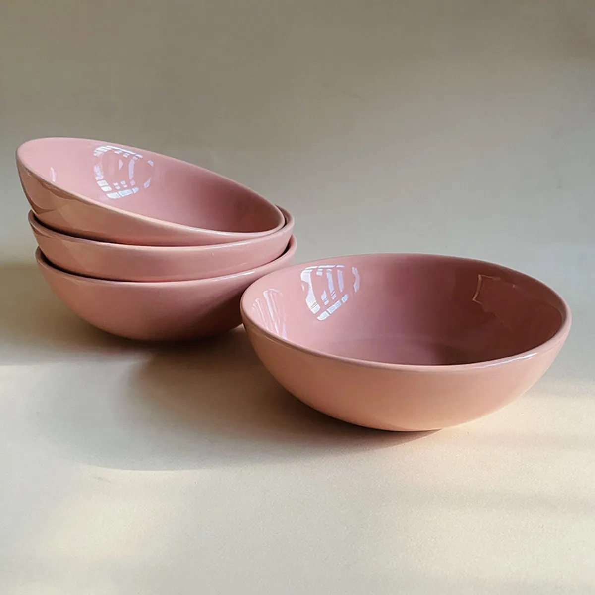 Three peach ceramic bowls stacked beside one separate bowl