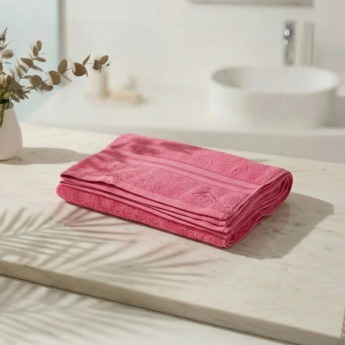 Folded pink bath towel displayed on a marble bathroom counter