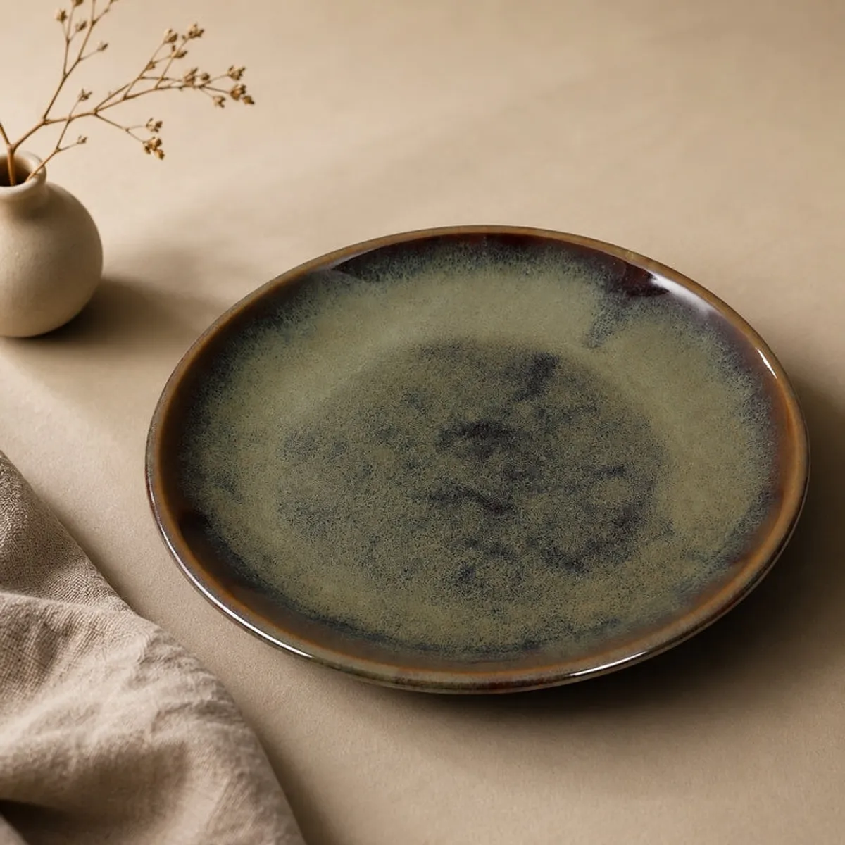 Close-up of an olive green round plate with mottled tonal finish
