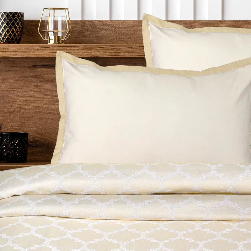 Close view of ivory pillow covers and folded geometric bedsheet