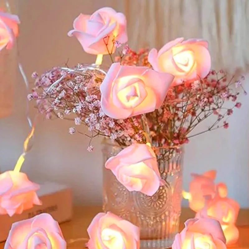 Glowing pink rose string lights draped around a glass vase