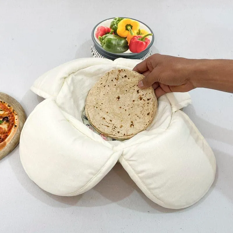 Hand lifting a roti from a white insulated-style bread basket