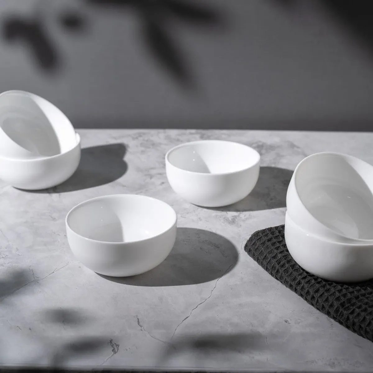 White round snack bowls arranged on a grey surface in soft directional light