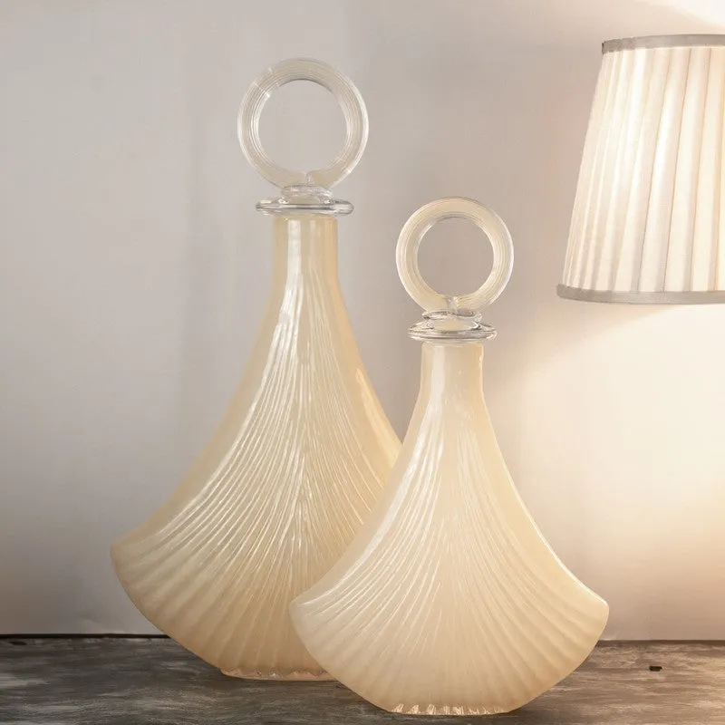 Two ivory glass vases displayed beside a lit table lamp