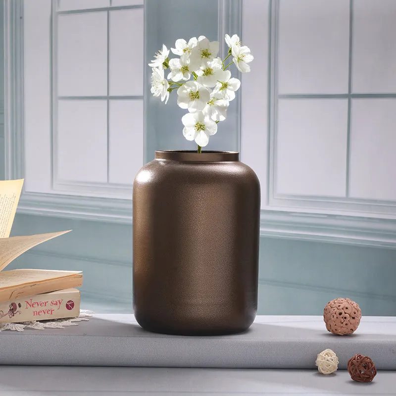 Brown metal vase with white flowers placed by a window