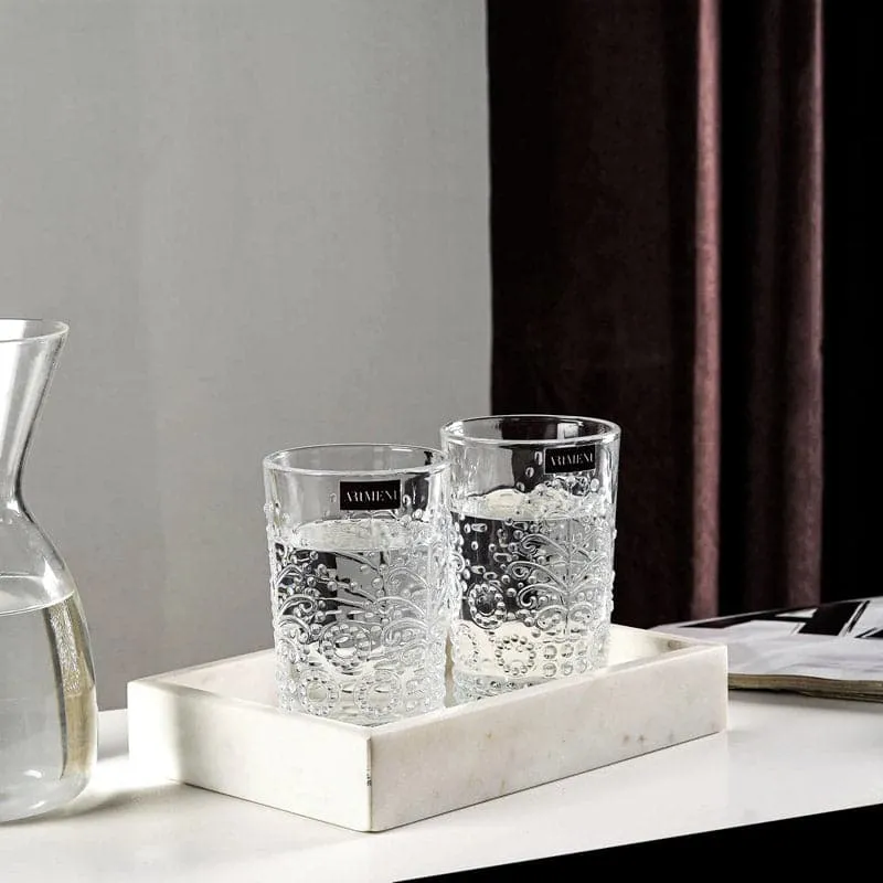 Two clear floral embossed glasses on a white tray