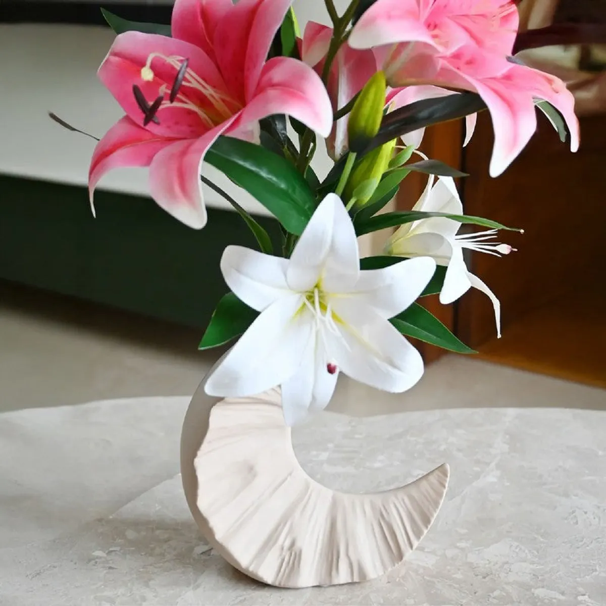 Half-moon vase styled with pink and white lilies on a tabletop
