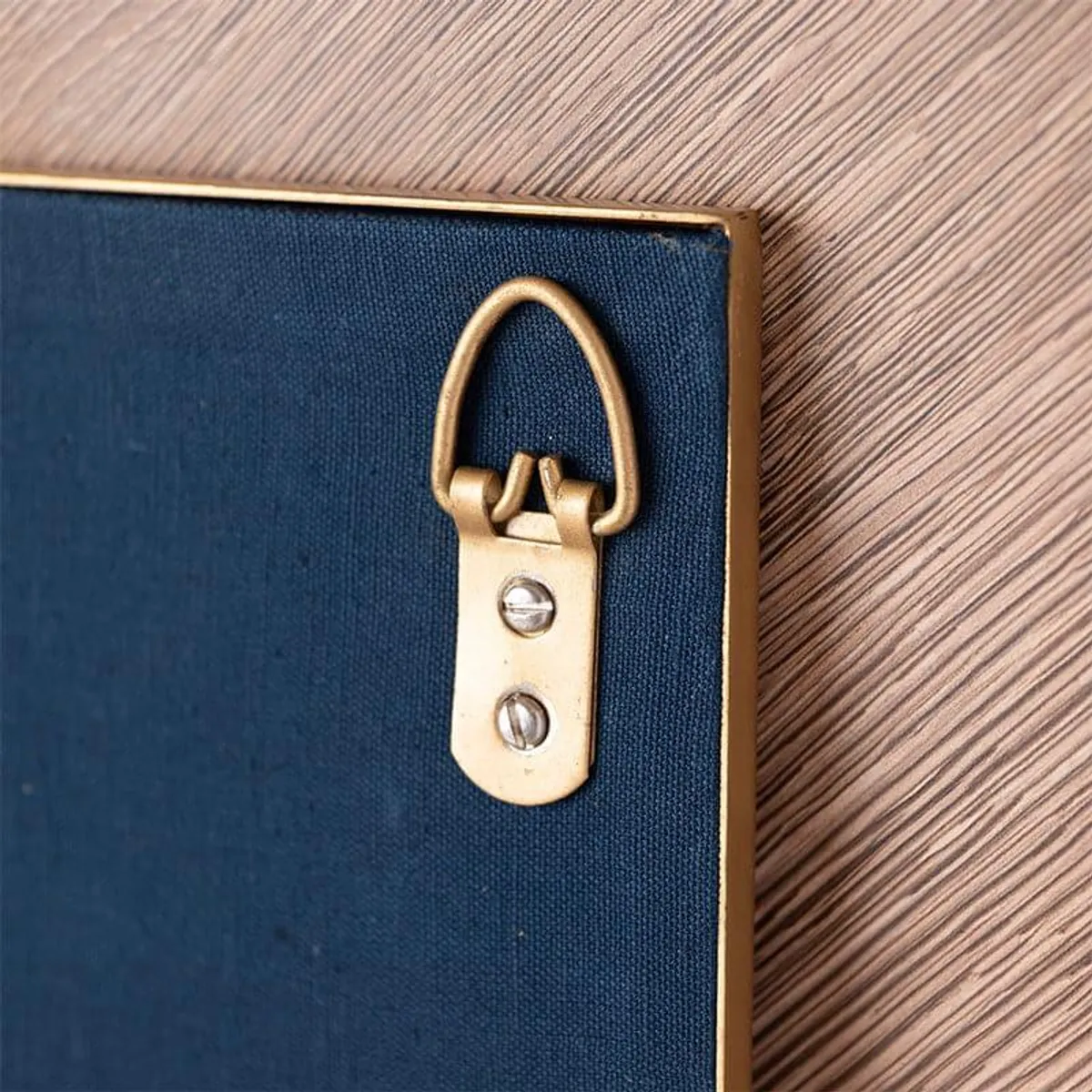 Close-up of a gold-toned wall-mount hanger on the back of the accent.