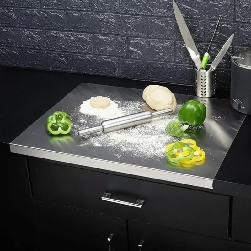 Steel rolling pin and board set with dough and flour on a dark countertop
