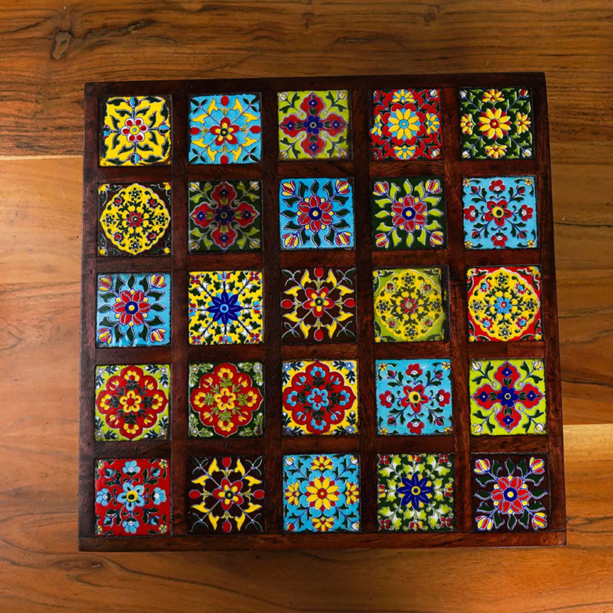 Top view of a square stool featuring a grid of colourful floral and geometric motifs
