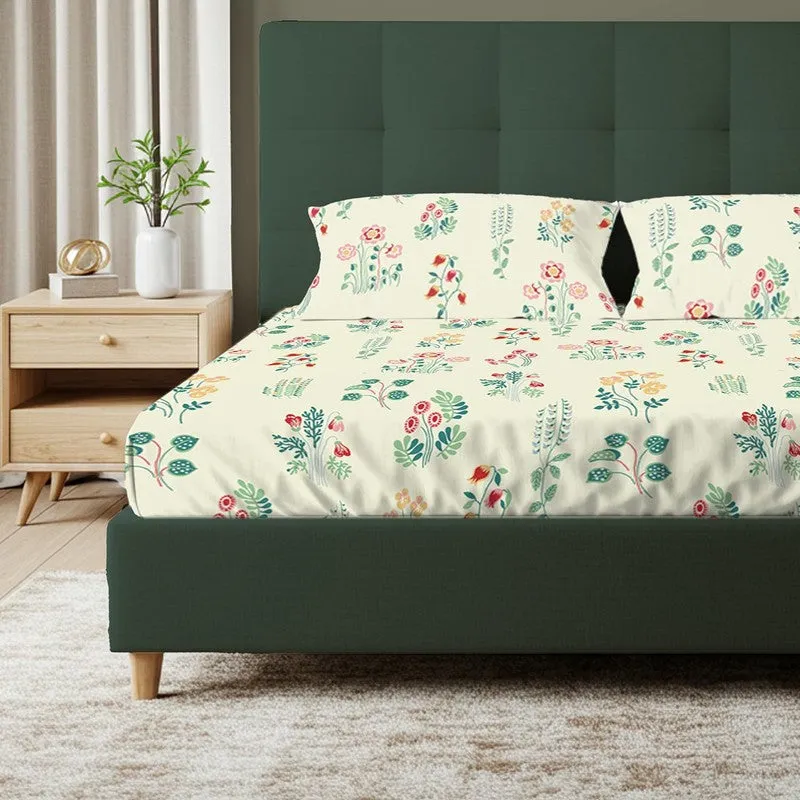Close view of floral fitted bedsheet and matching pillow covers on a green bed