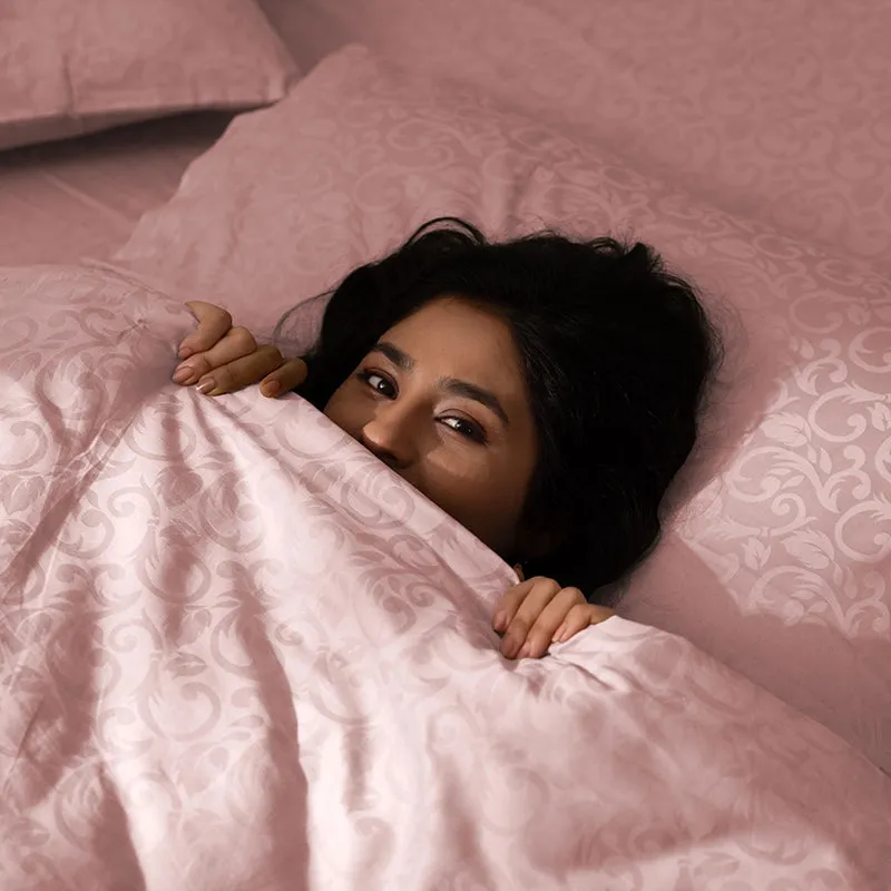 Person relaxing beneath a pink floral duvet cover