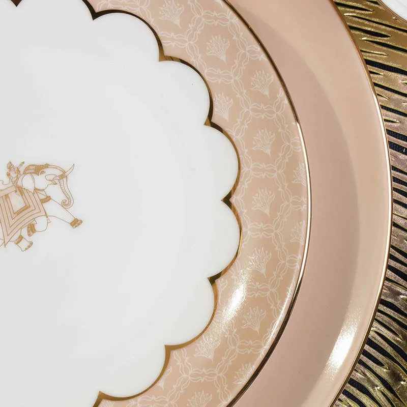 Close-up of scalloped ivory and peach plate with delicate gold pattern