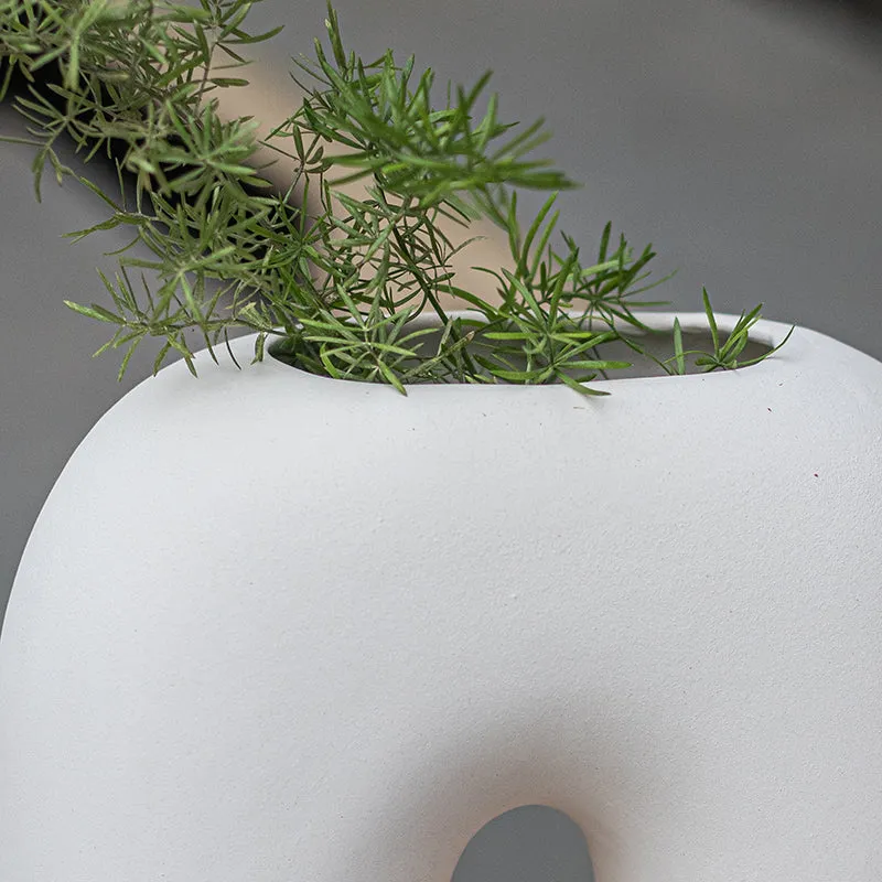 Close-up of the white ceramic arc vase with green stems