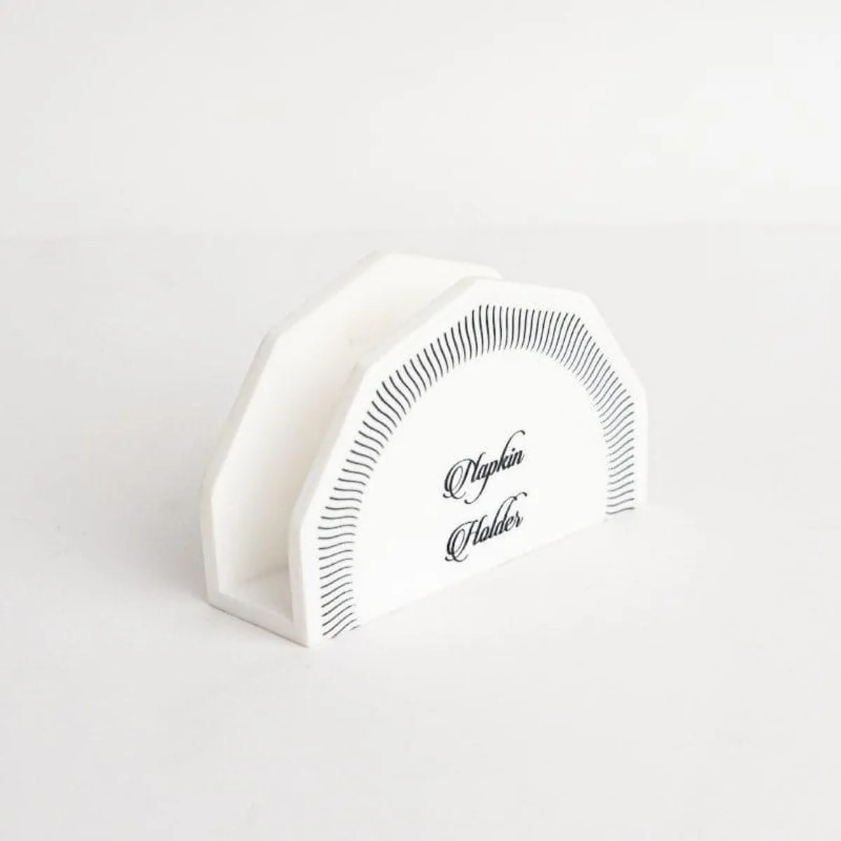 White marble napkin holder with black line detailing on an angular front panel.