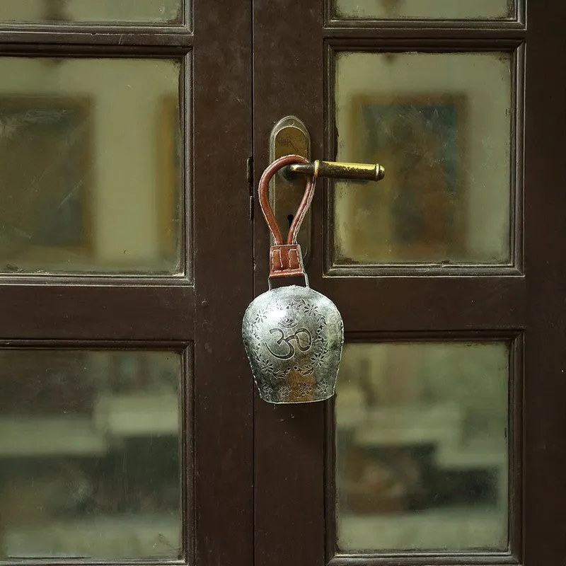 Silver decorative bell hanging from a dark wooden door