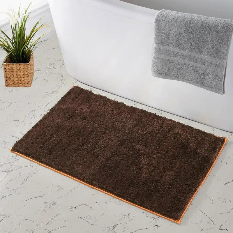 Brown rectangular bath mat beside a white bathtub