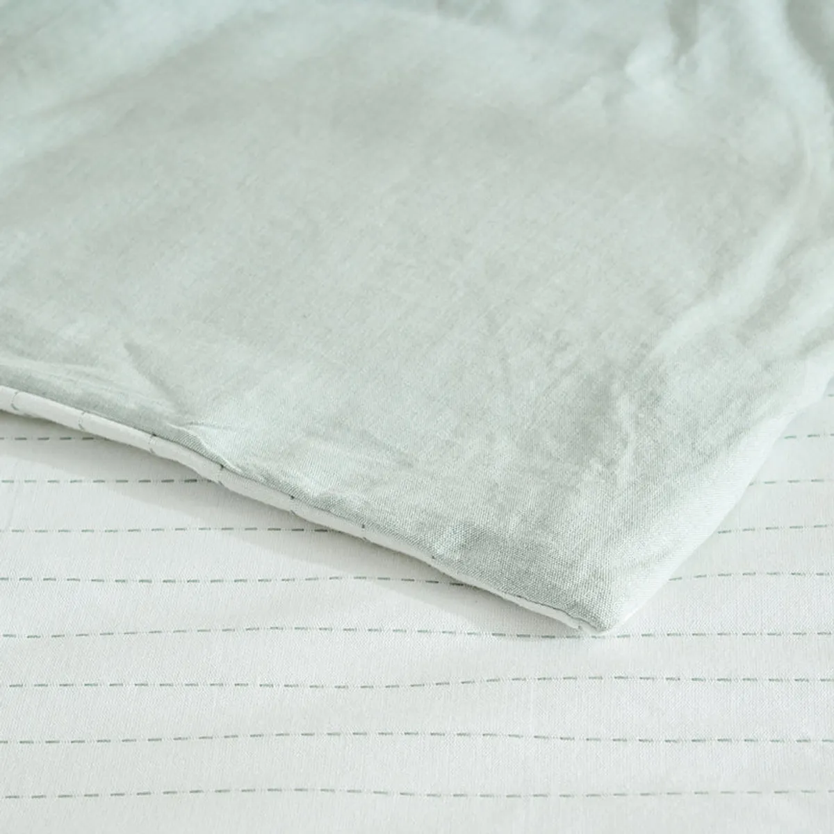 Pale mint fabric draped over white striped bedding