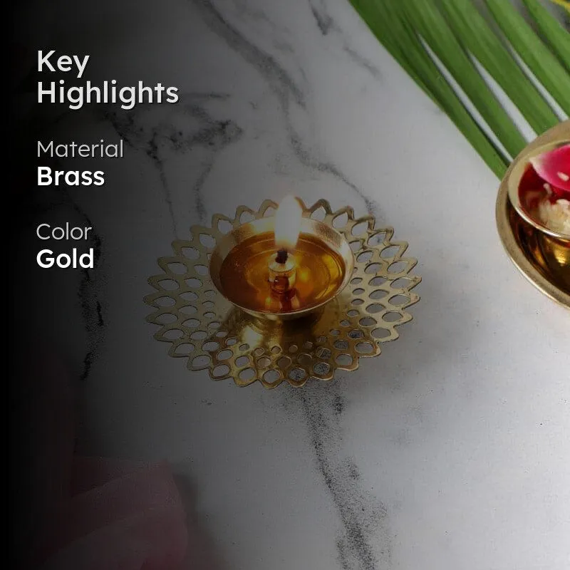 Lit brass diya with gold finish on a marble surface
