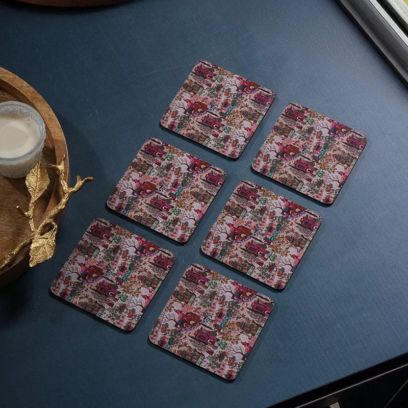 Six printed coasters arranged on a dark tabletop beside a serving tray