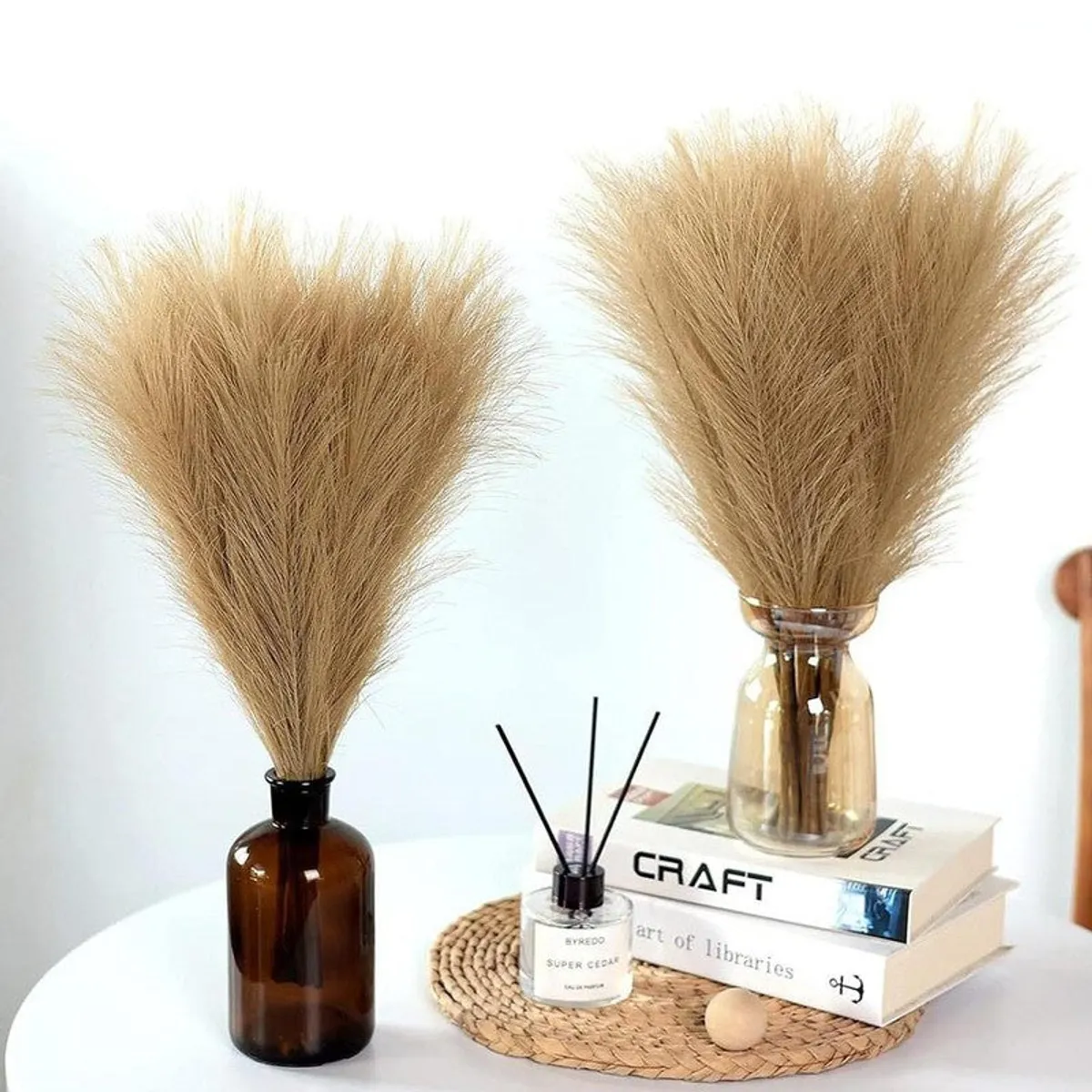Two brown pampas arrangements styled with books and home accessories