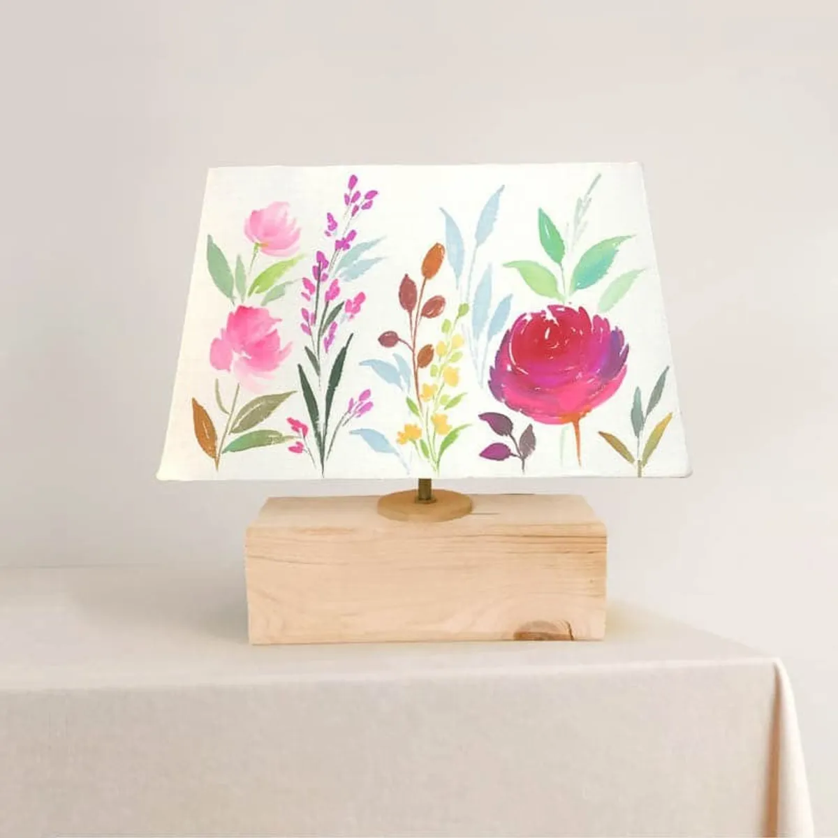 Floral fabric table lamp showing pink, green and blue flowers on a rectangular shade