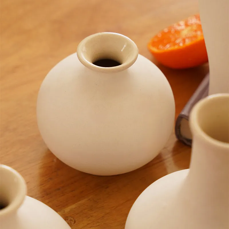 Close-up of a round white ceramic vase on a wooden tabletop