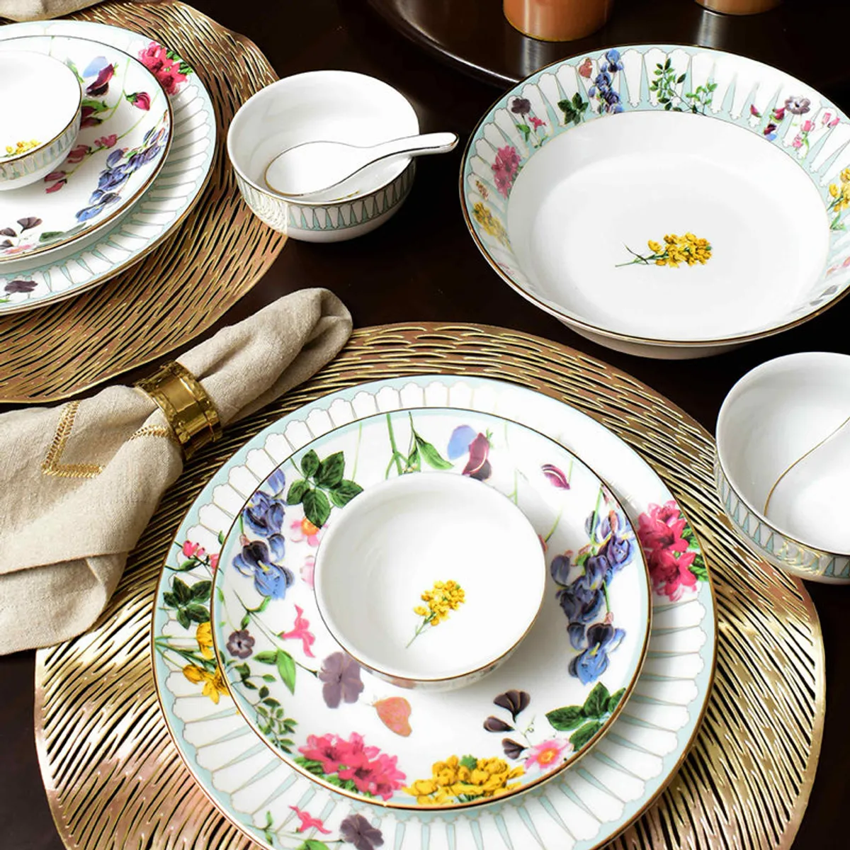 Basant dinnerware arranged on a dining table with floral plates and bowls