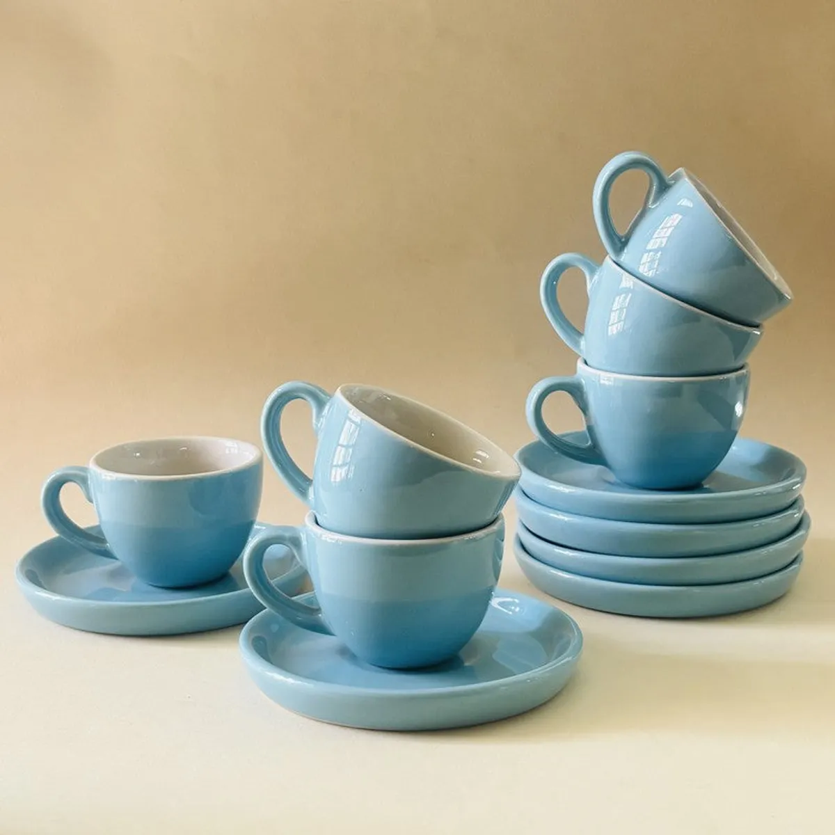 Blue ceramic tea cups and saucers arranged across a warm tabletop