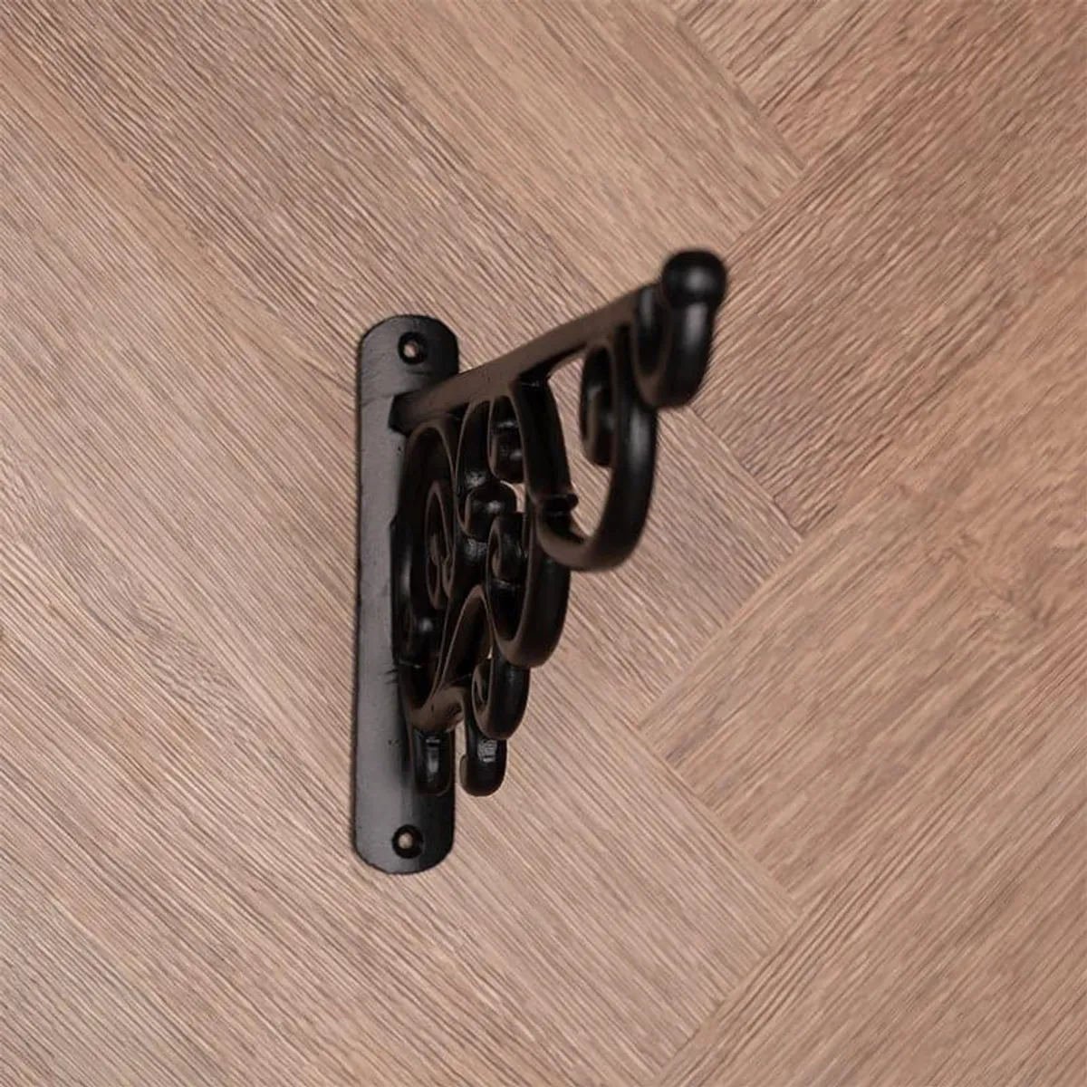 Side view of a black metal wall bracket showing its curved scrollwork profile.