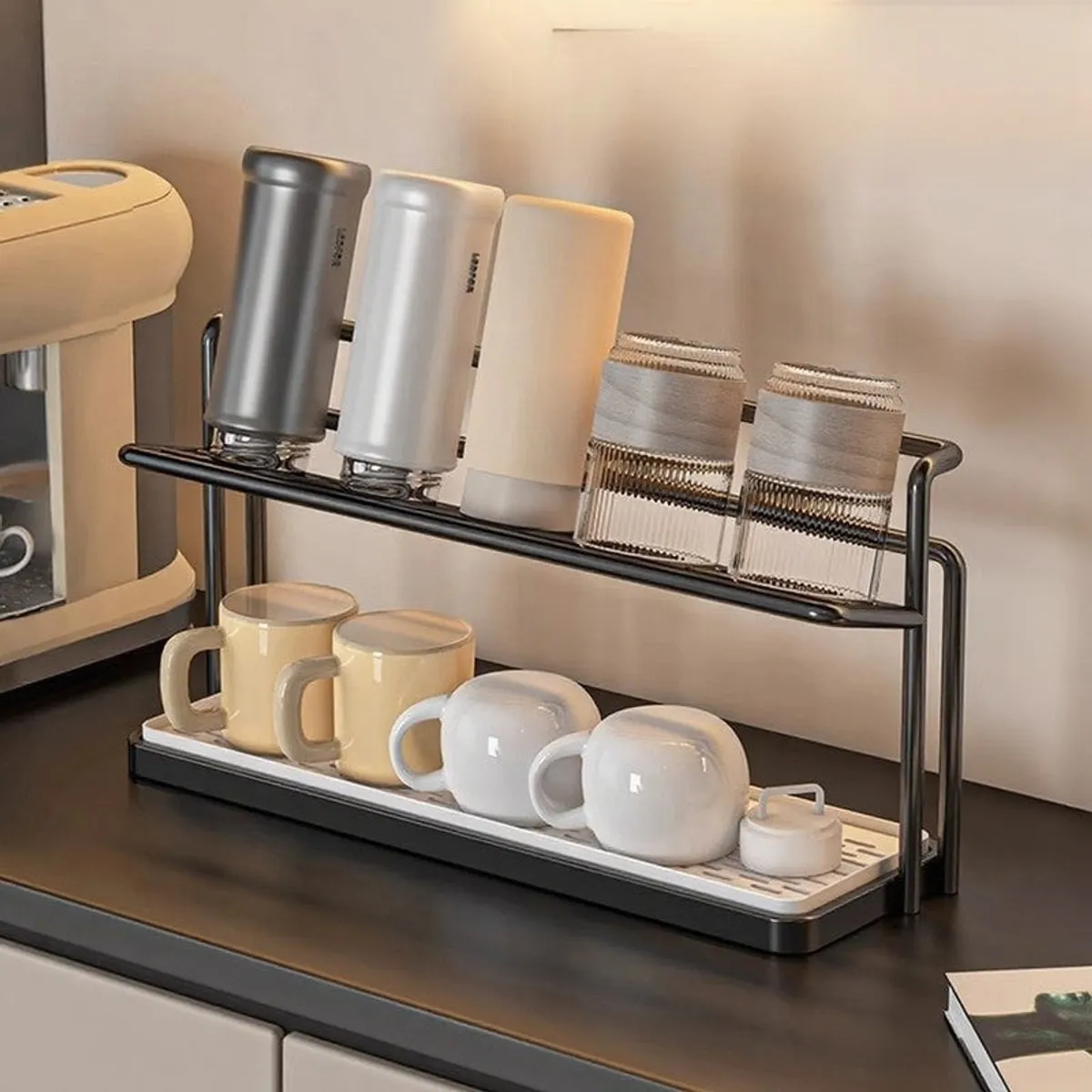 Black two-tier organiser with cups, bottles and glasses on a kitchen counter
