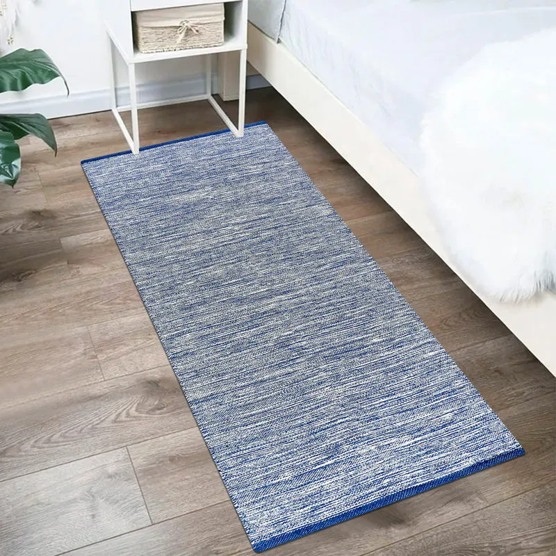 Blue runner rug placed beside a bed on a wooden floor