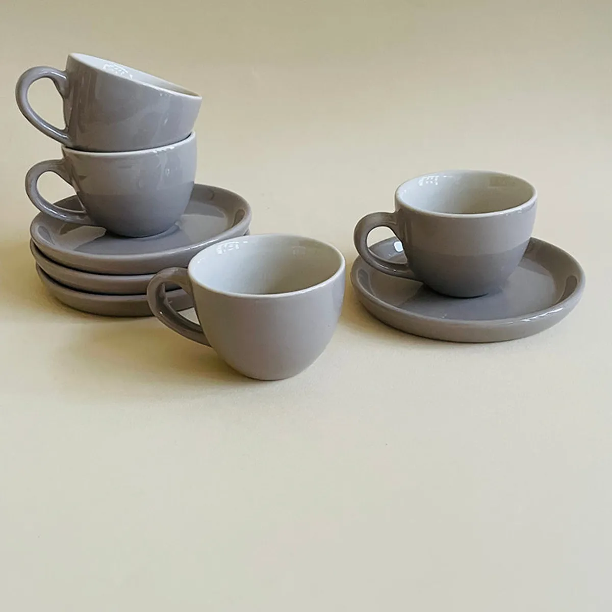 Grey ceramic cups and saucers arranged with two cups stacked