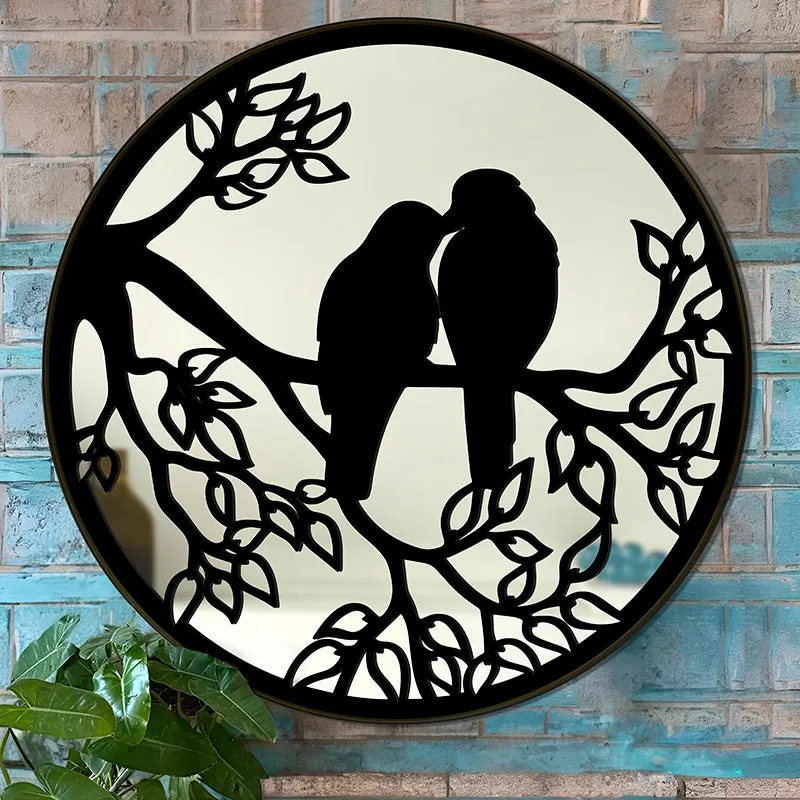 Close view of round black mirror with lovebirds and leafy branches
