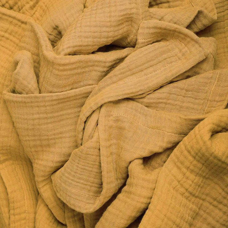 Folded and draped yellow textured bedsheet showing its softly crinkled surface