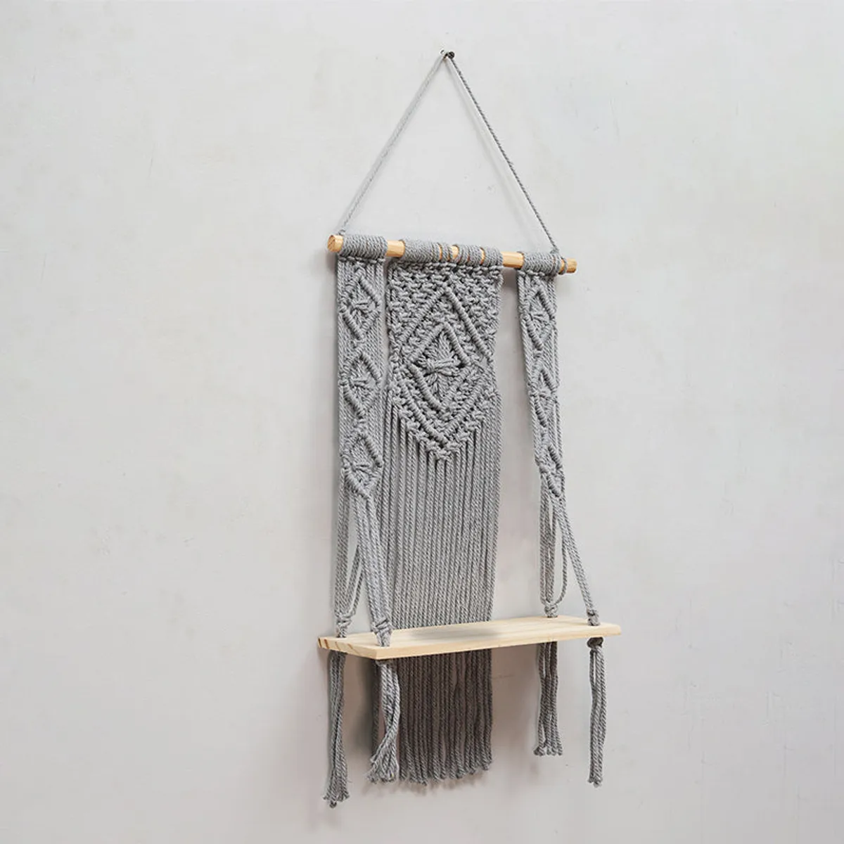 Angled view of a grey macrame wall shelf