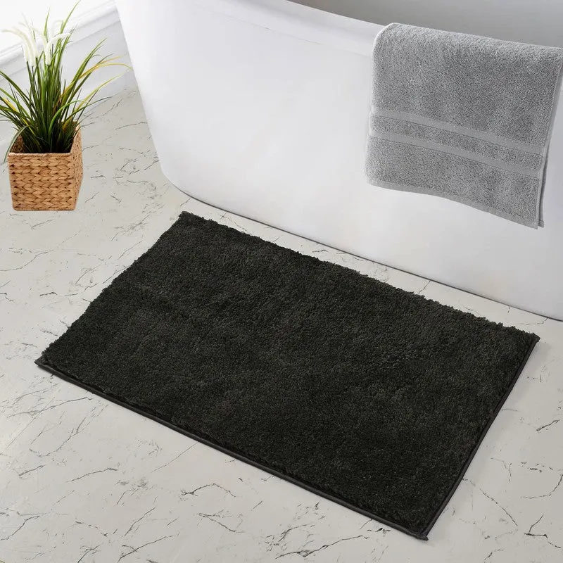 Dark grey bath mat beside a bathtub on a marble floor