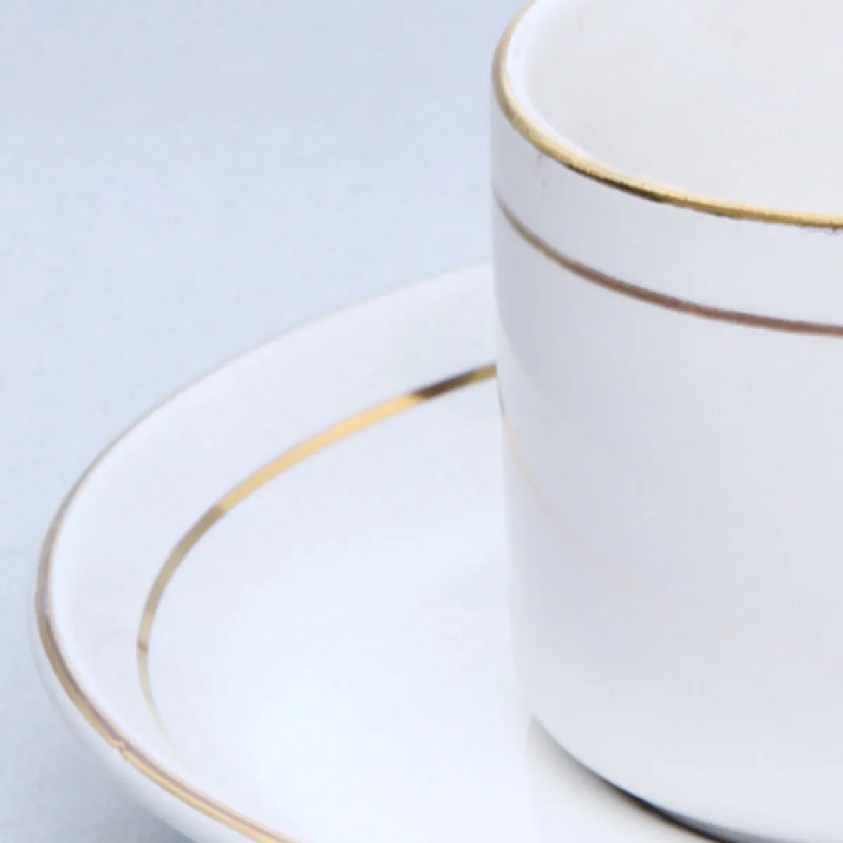 White cup and saucer with gold trim shown in close-up