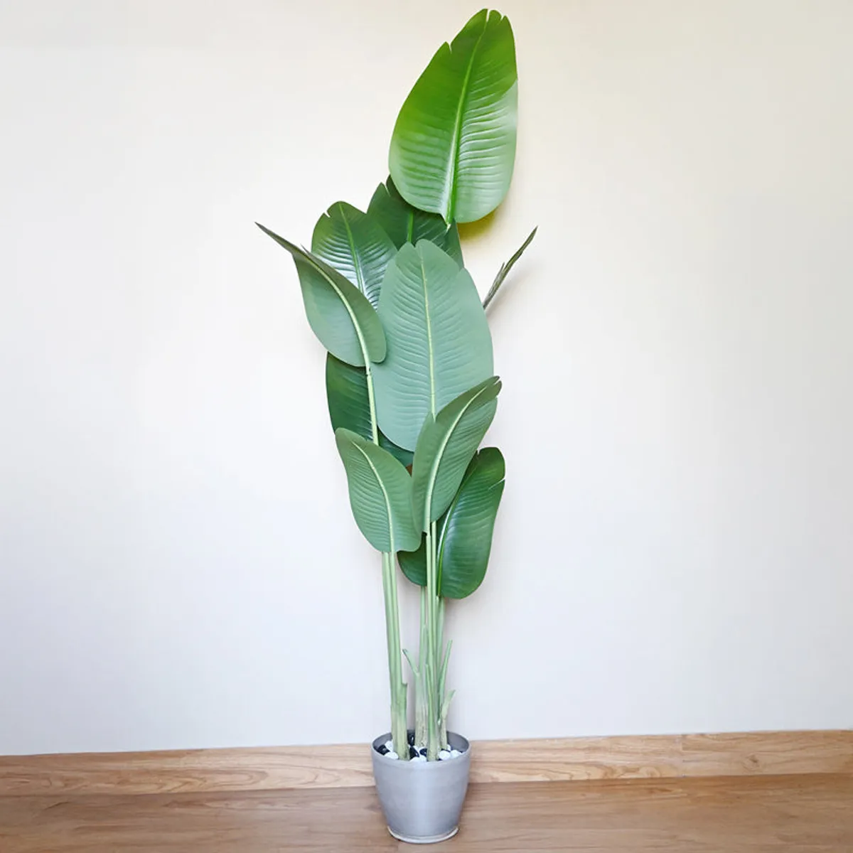 Tall artificial Bird of Paradise plant with broad green leaves in a black pot