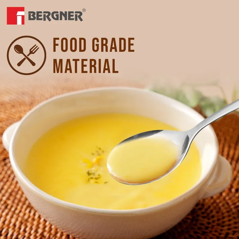 Silver soup spoon held over a bowl of yellow soup