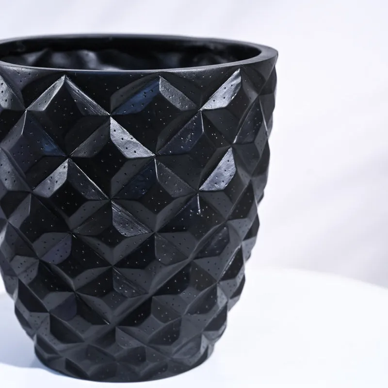 Close-up of black planter with faceted geometric textured pattern